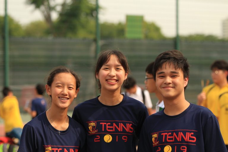 Three ACS(I) tennis team members in Tennis 2019 shirts pose together for a photo at a team gathering or event.